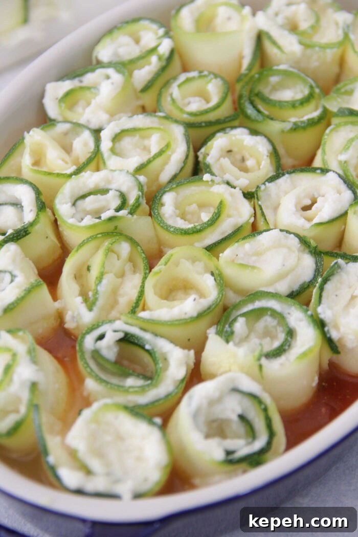 Zucchini Lasagna Roll-Ups with Ricotta & Marinara 3 Zucchini Lasagna Roll Ups unbaked in a blue baking dish