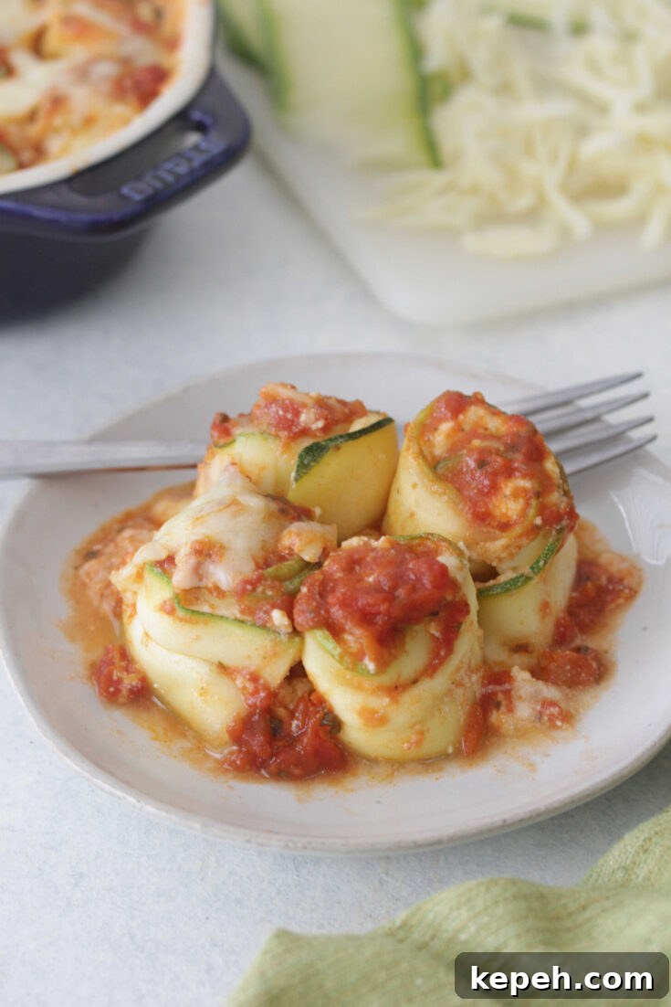 Zucchini Lasagna Roll Ups on a white place with tomato sauce on top