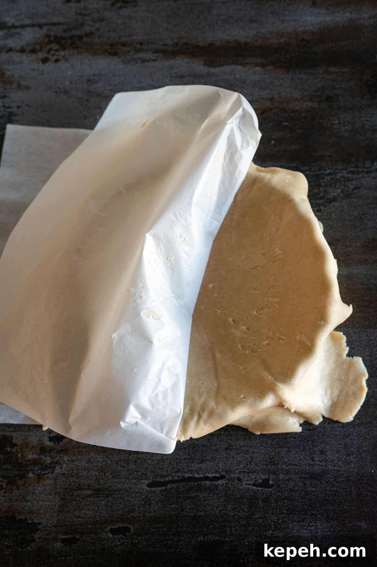 Flaky Pie Crust Recipe for Sweet and Savory Pies 11 pie crust in tin, peeling off parchment paper.