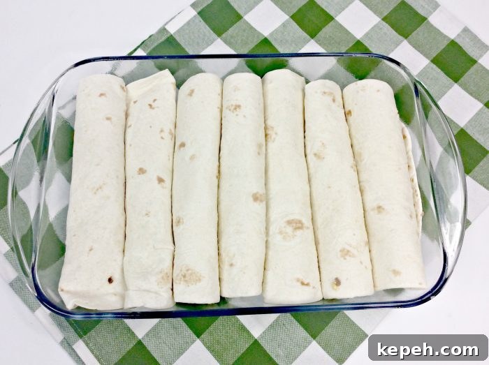 tortillas in a glass baking dish on a green and white towel.