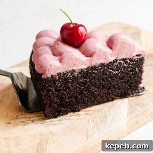 Slice of chocolate olive oil cake topped with cherry ganache on a serving board.