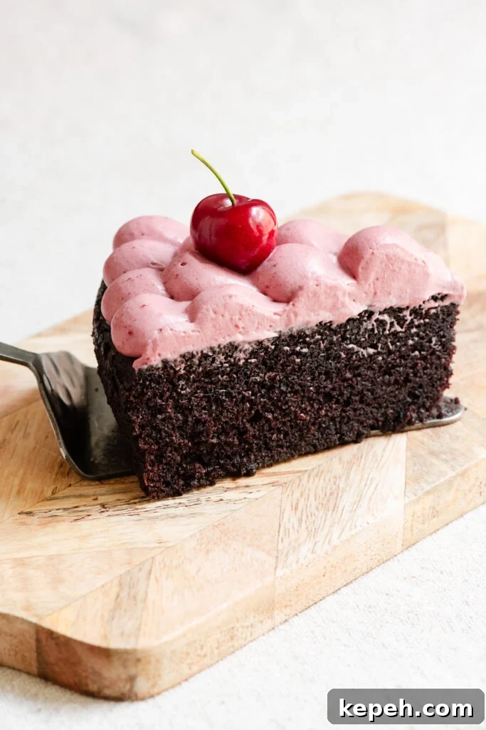 Slice of chocolate olive oil cake topped with cherry ganache on a serving board.