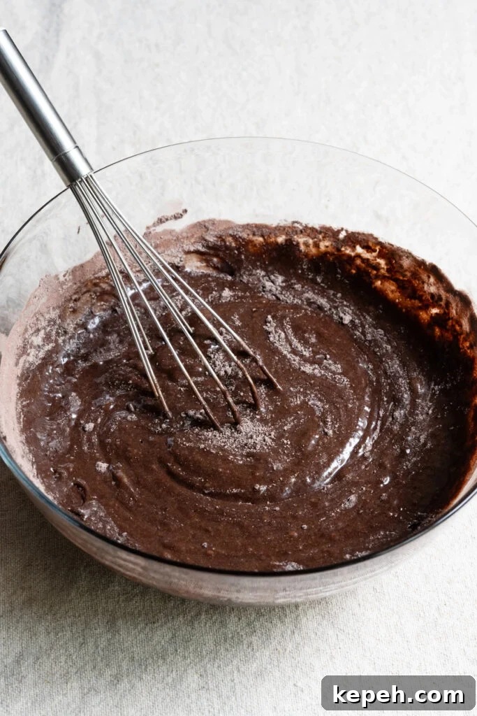 Whisk in a bowl with chocolate cake batter.