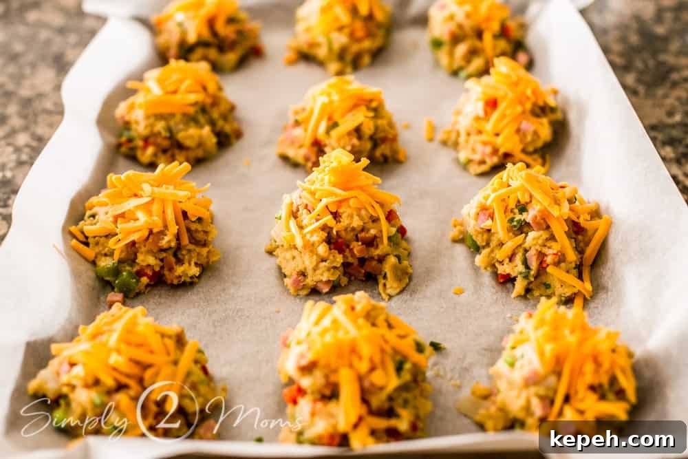 cookie sheet lined with parchment paper with unbaked keto southwest breakfast biscuits topped with cheese