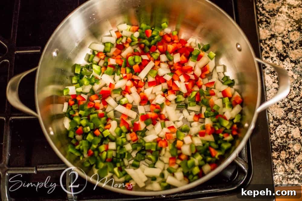 overhead view of chopped onions and peppers in a large pan on top of the stove