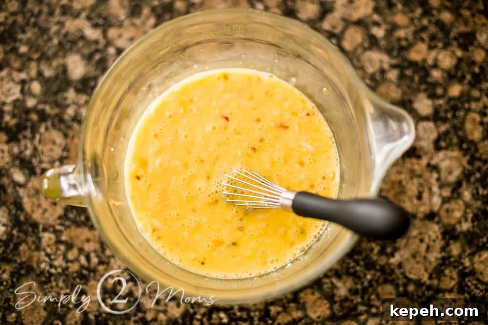 overhead view of a mixing bowl with eggs whisked together