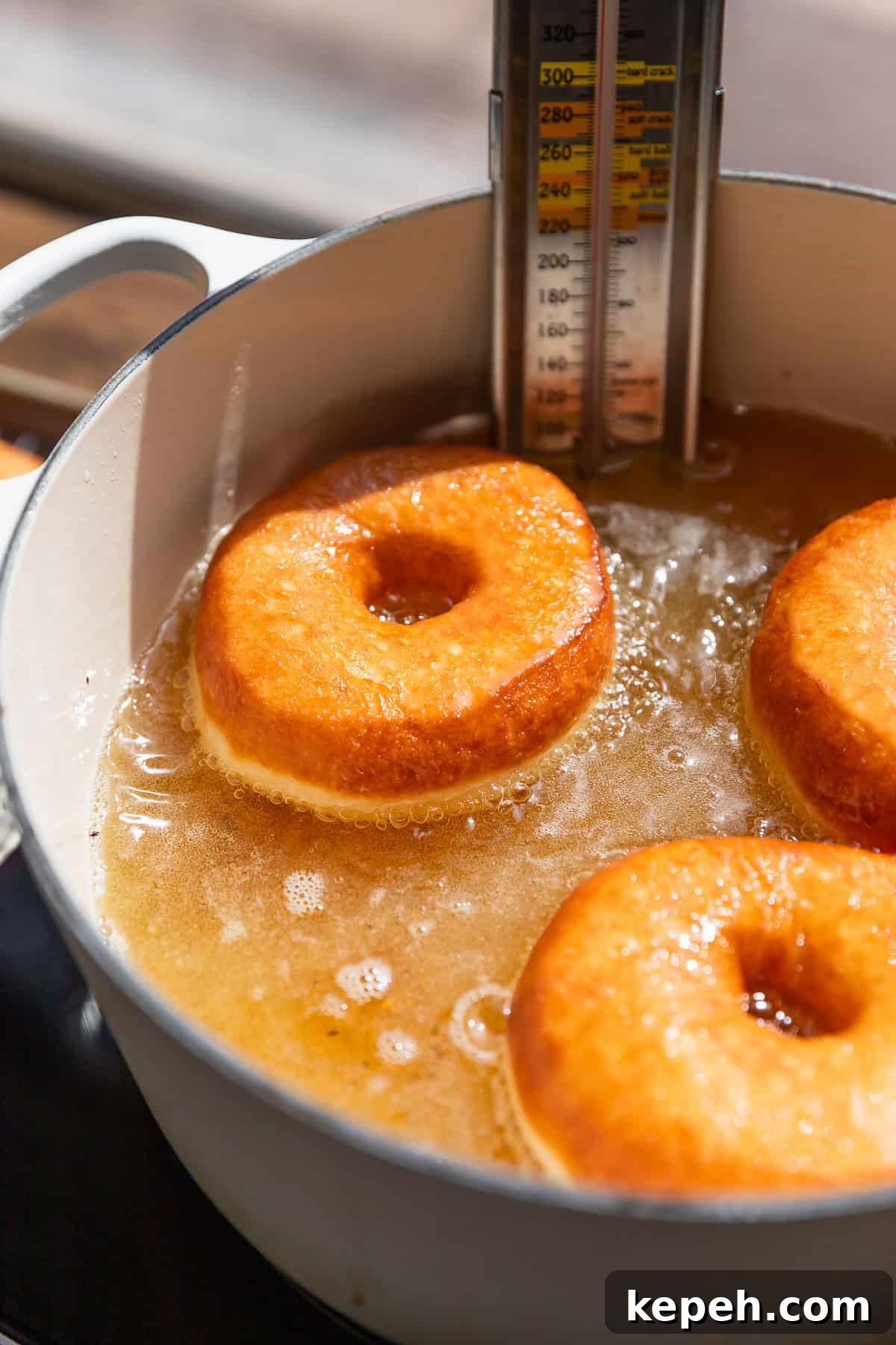 Salted Caramel Donuts with Shiny Caramel Glaze 8 Three donuts frying in hot oil.
