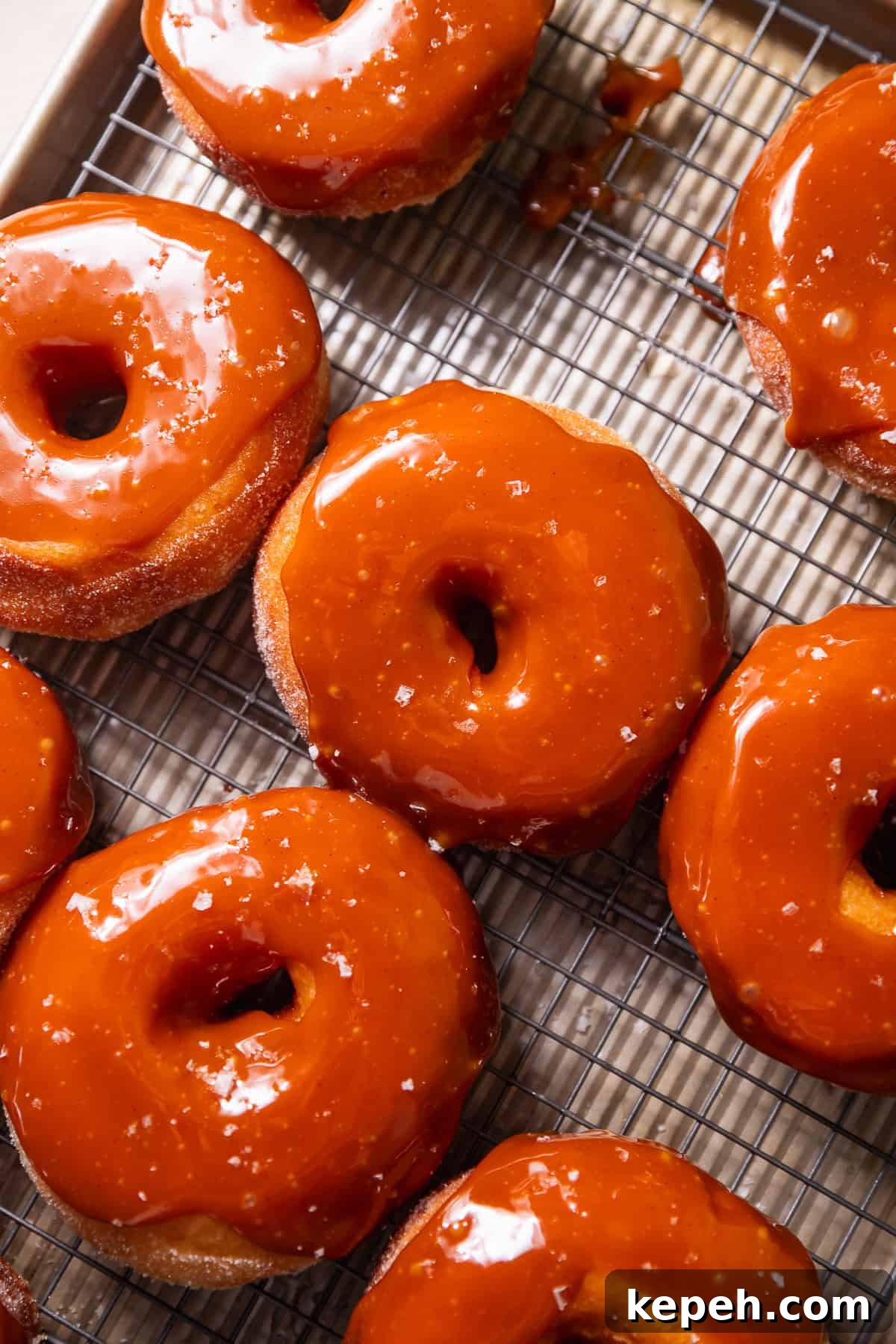 Salted Caramel Donuts with Shiny Caramel Glaze 10 A wire rack with salted caramel donuts on top.