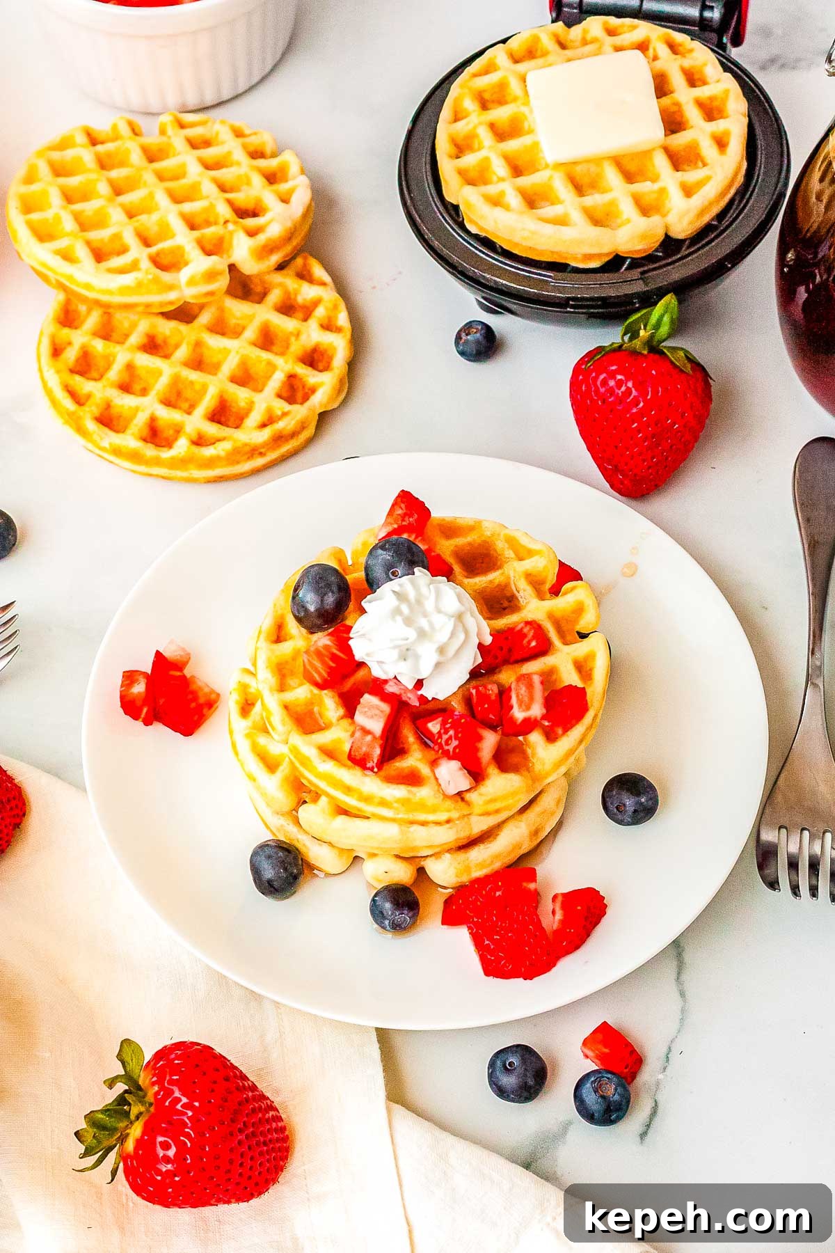Crispy Dash Waffle Maker Recipes for Quick Breakfasts 8 Three waffles on a plate topped with syrup, berries, and whipped cream.