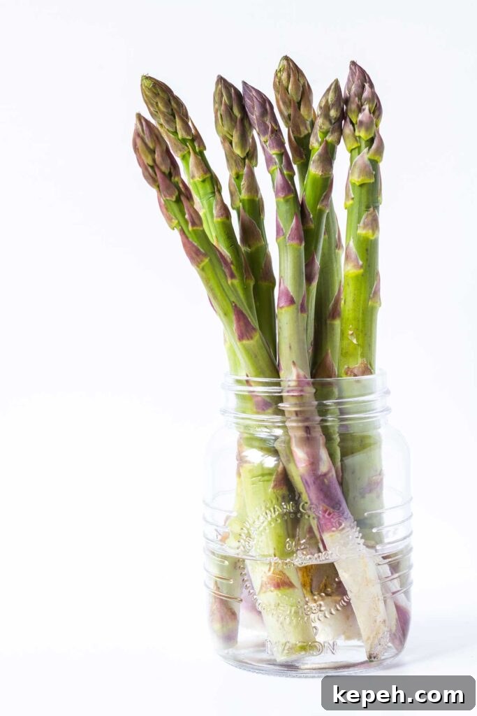 How to Store Asparagus for Maximum Freshness 2 Asparagus on a small glass jar filled with water.