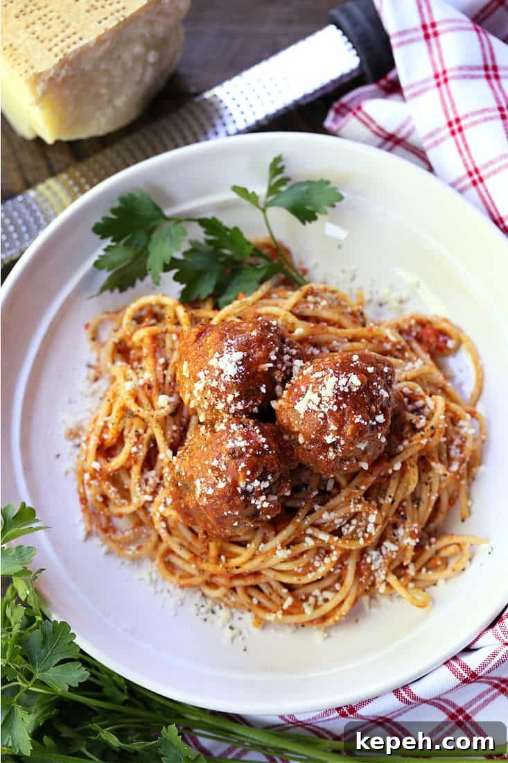 Spaghetti and Slow Cooker Meatballs Spaghetti and meatballs on a white plate with parsley