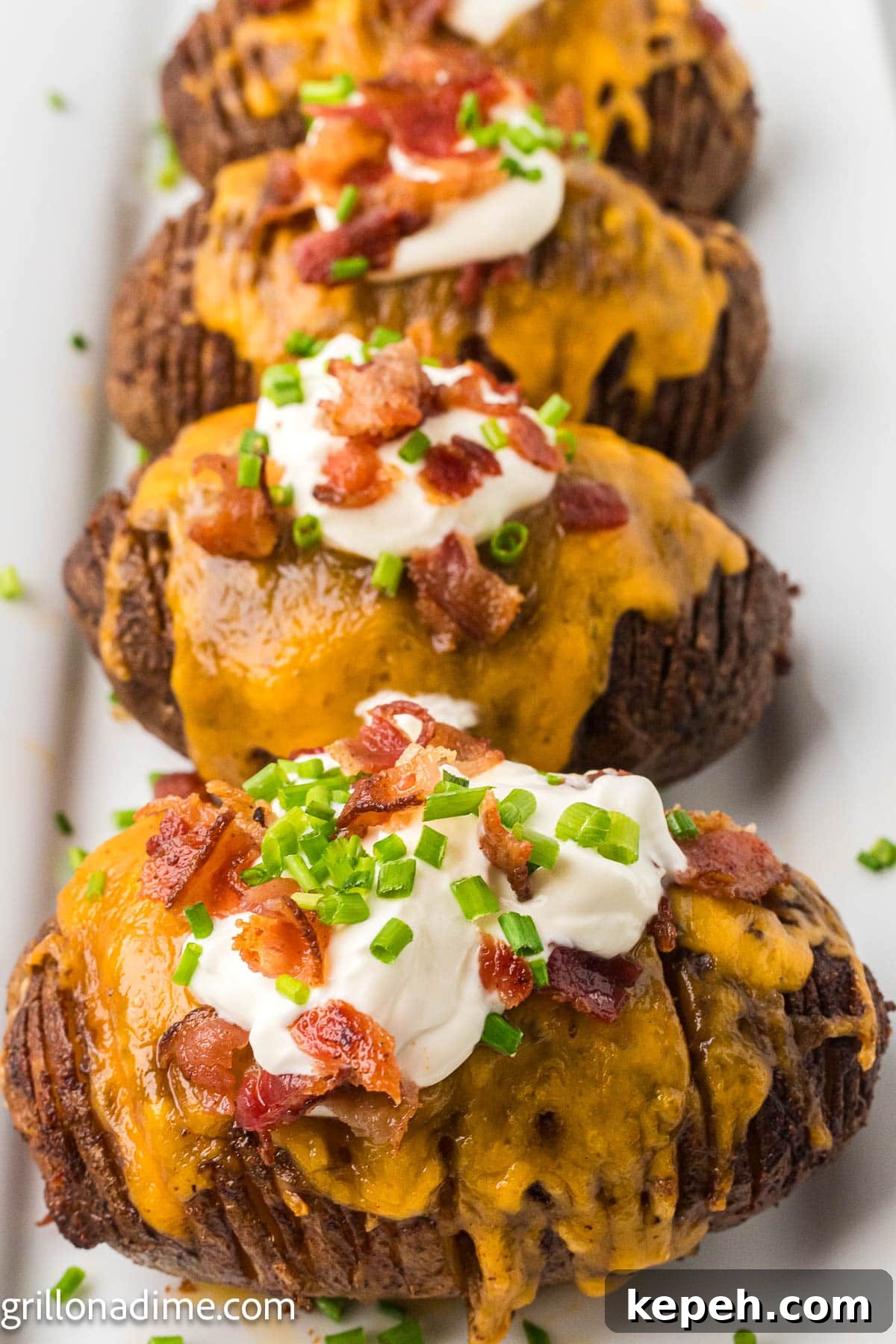 Smoked Hasselback Potatoes with Crispy Herb Butter 2 Hasselback potatoes topped with cheese, bacon, sour cream and chives