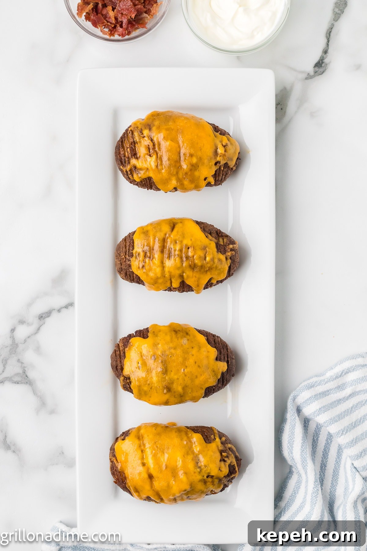 Smoked Hasselback Potatoes with Crispy Herb Butter 7 Smoked hasselback potatoes on a platter topped with melted cheese