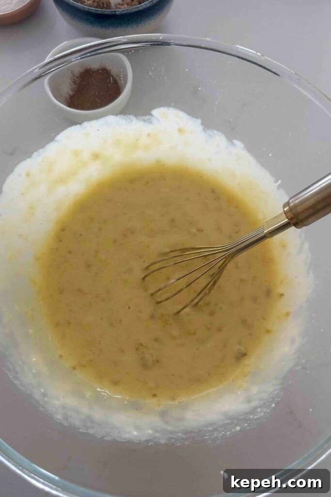 Sourdough Banana Bread with Hawaiian-Style Sweetness 6 Mashed bananas with vanilla, melted butter, sourdough starter and an egg mixed in a glass bowl to make sourdough Hawaiian banana bread.