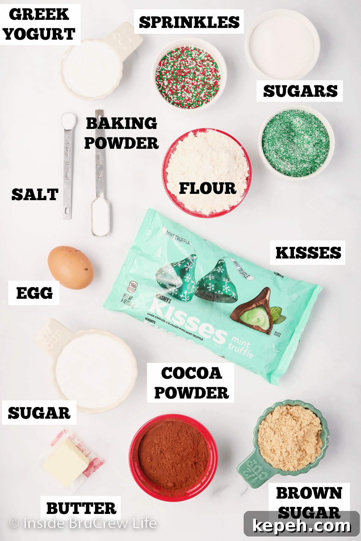 A white board with bowls of ingredients for chocolate kiss cookies.