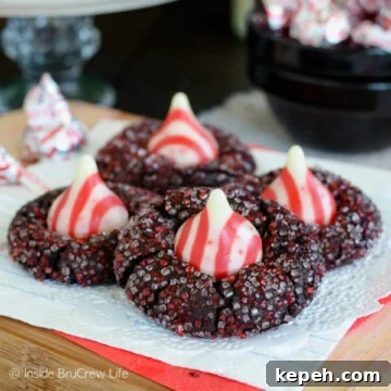 Four chocolate kiss cookies with red and white sugar and a candy cane kiss.