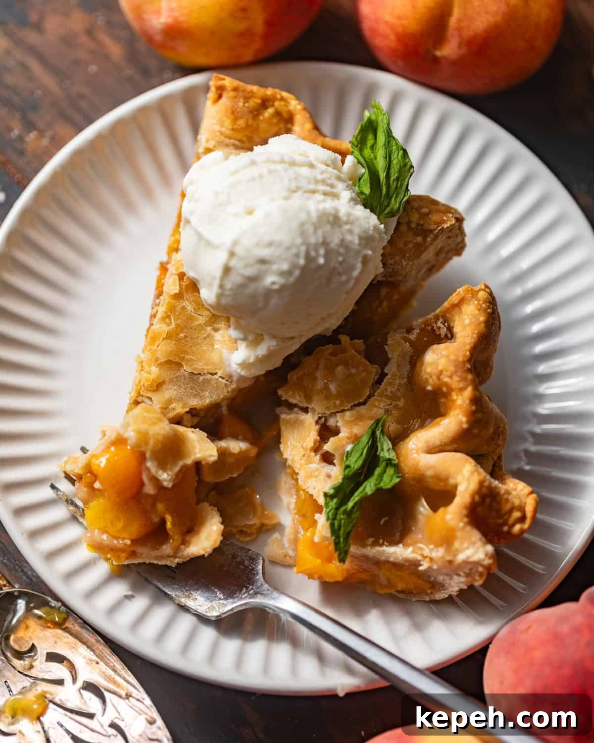 Perfect Peach Pie Recipe Using Canned Peaches 2 sliced peach pie on a plate topped with ice cream and mint.