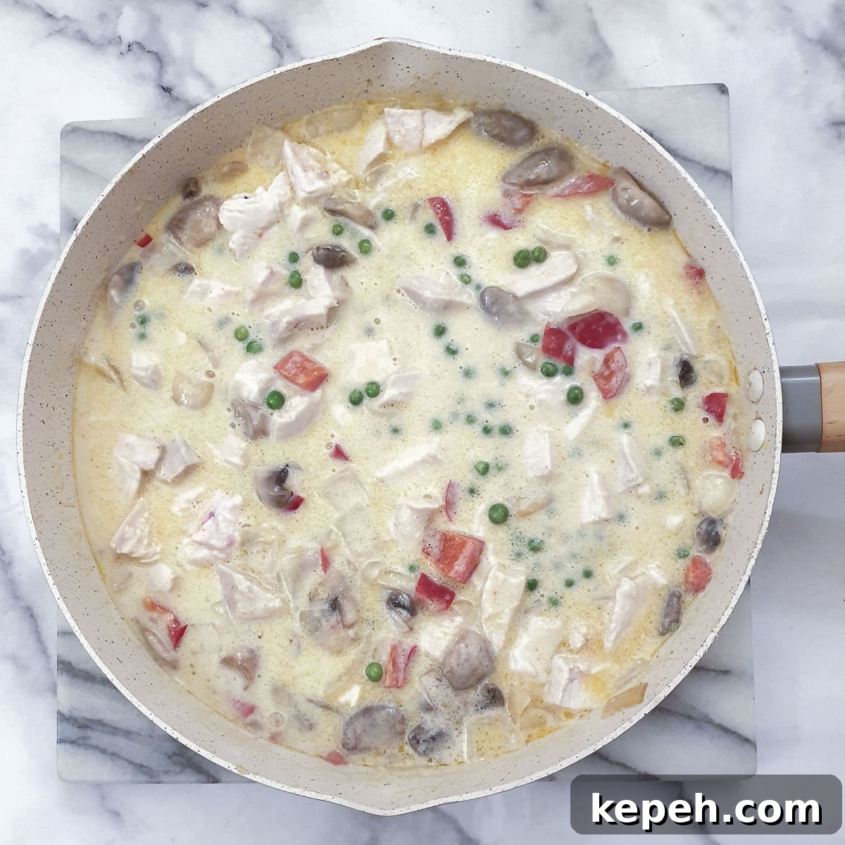 Classic Chicken à la King Recipe: Creamy One-Pot Dinner 12 Peas and chicken added to the sauce in a frying pan.