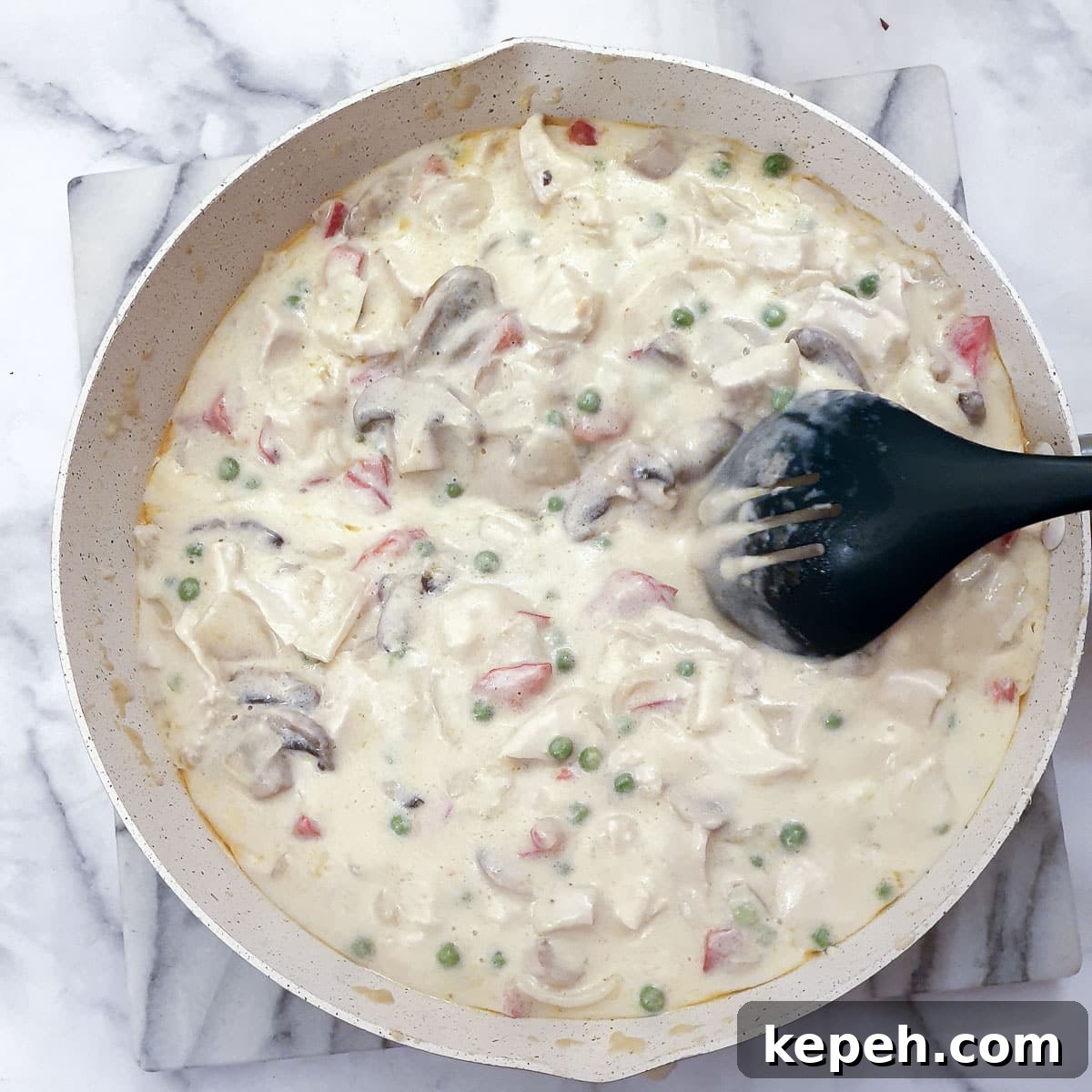 Classic Chicken à la King Recipe: Creamy One-Pot Dinner 13 A spoon being drawn through a pan of chicken a la king sauce.