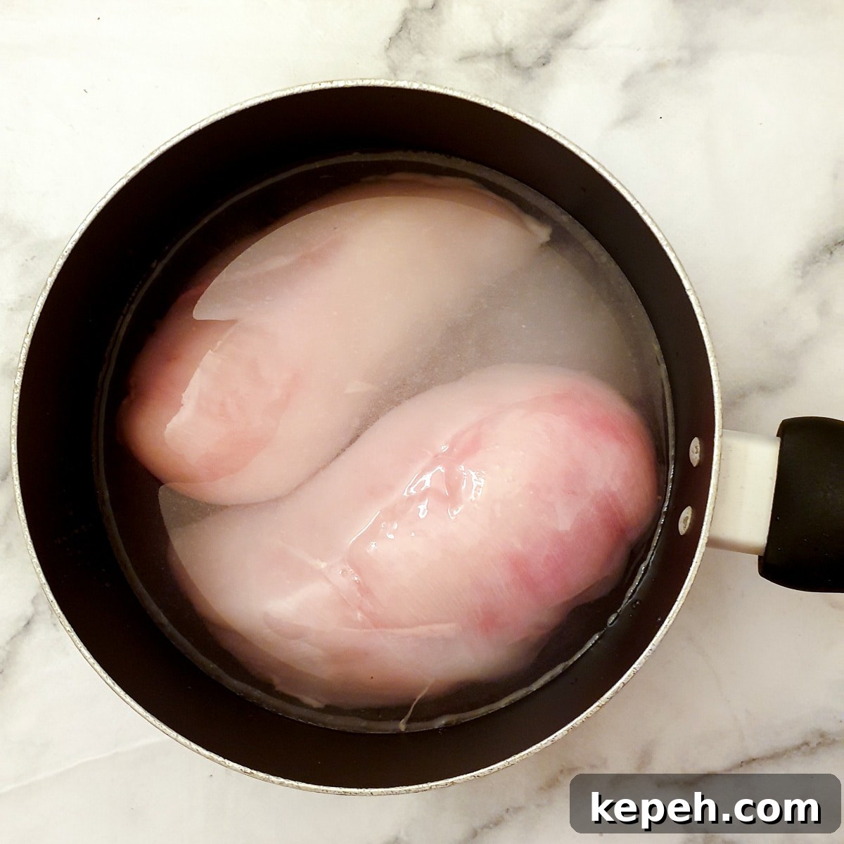 Classic Chicken à la King Recipe: Creamy One-Pot Dinner 5 Two chicken breasts in a saucepan of water.