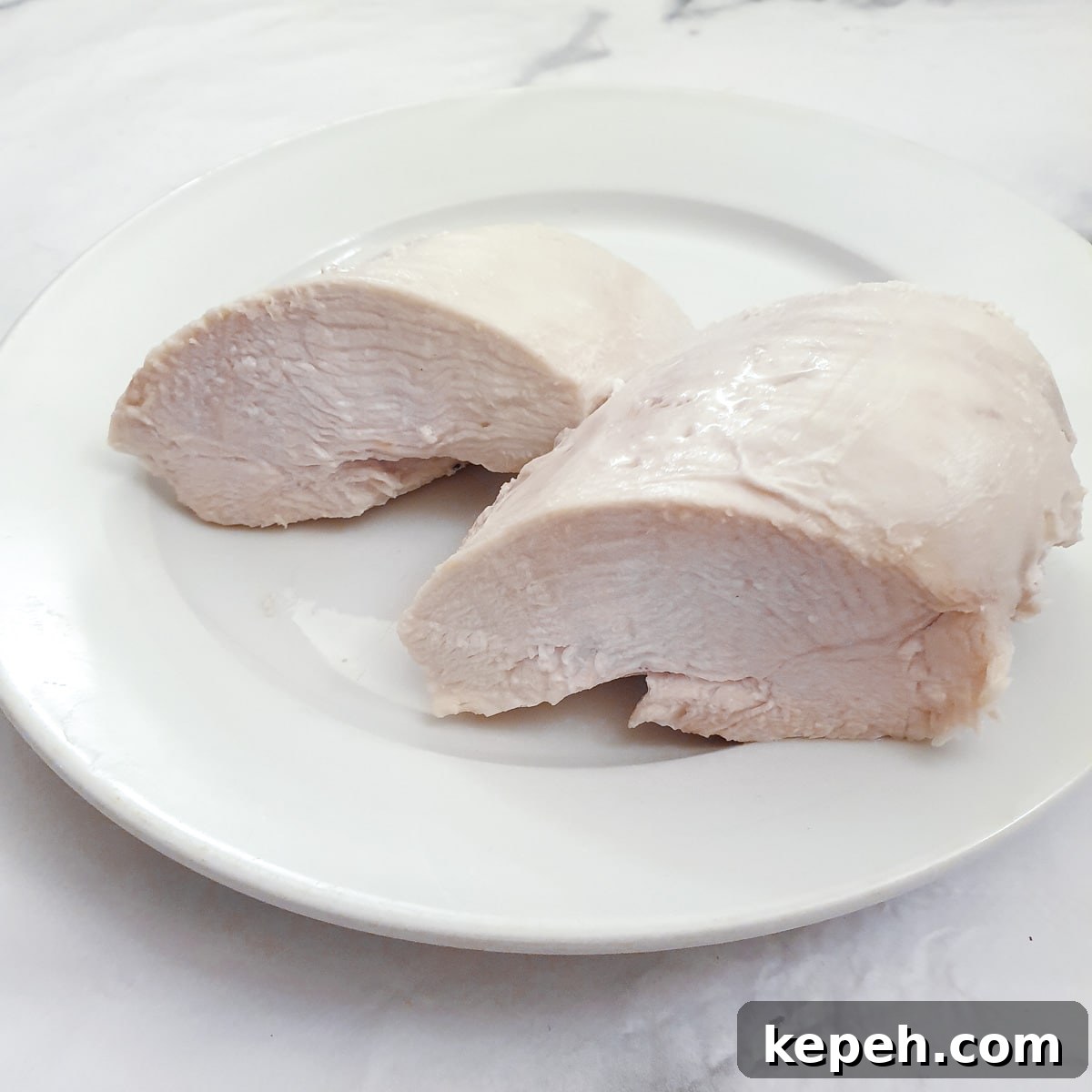 Classic Chicken à la King Recipe: Creamy One-Pot Dinner 6 A poached chicken breast cut in half on a white plate.