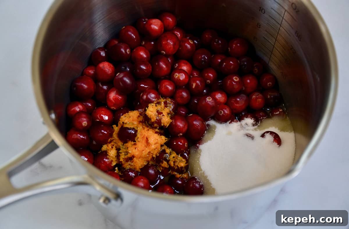 Sparkling Cranberry Champagne Cocktail Recipe for Holidays 3 Cranberries, sugar, orange zest and juice, Grand Marnier and water in a stainless steel saucepan.
