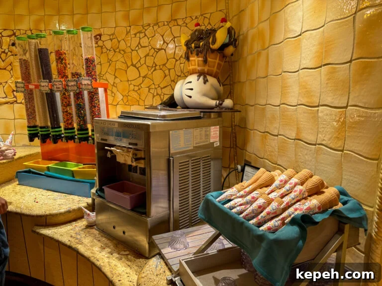 Soft serve ice cream machine with a stack of waffle cones on one side and containers of sprinkles and other toppings on the other side with Goofy's hand on top of the machine.