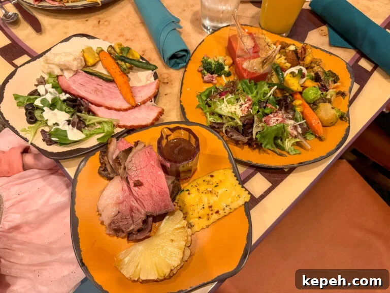 Plates with salad, prime rib, crab legs, ham, roasted vegetables, grilled pineapple and ravioli on a table at Goofys Kitchen.