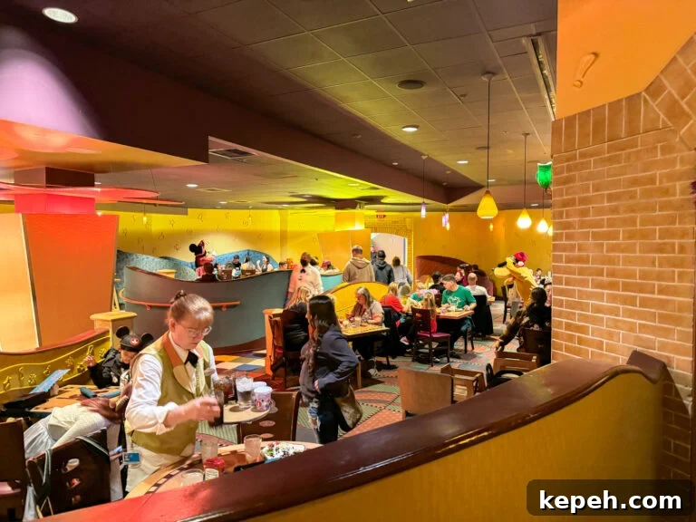Yellow and red walls with fun patterns on the carpet and lots of guest tables at Goofy's Kitchen Restaurant at Disneyland.
