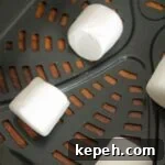 Uncooked marshmallows in an air basket, evenly spaced.