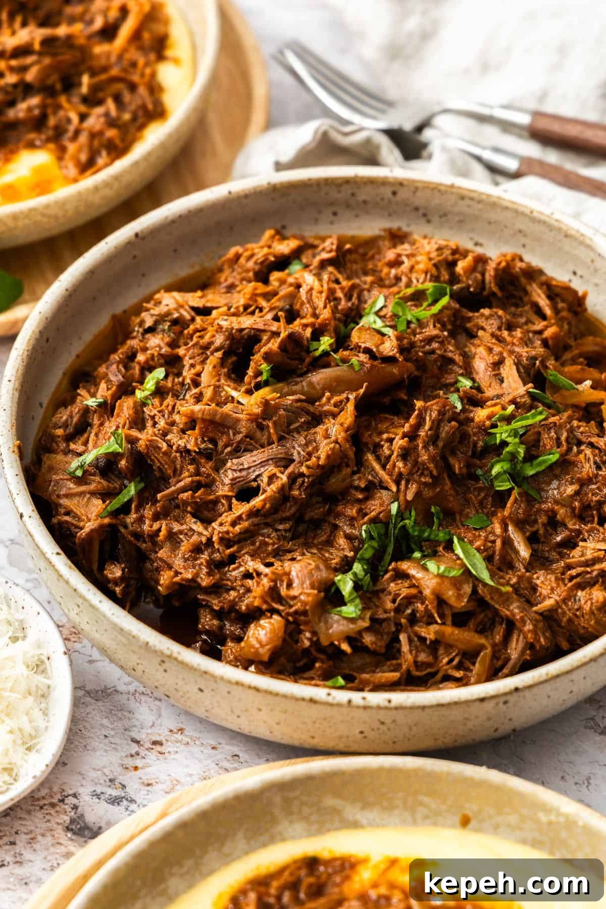 Top Easter Main Courses for a Memorable Holiday Meal 11 Round dish of Mediterranean Pulled Beef garnished with fresh basil, sitting on a white cloth.