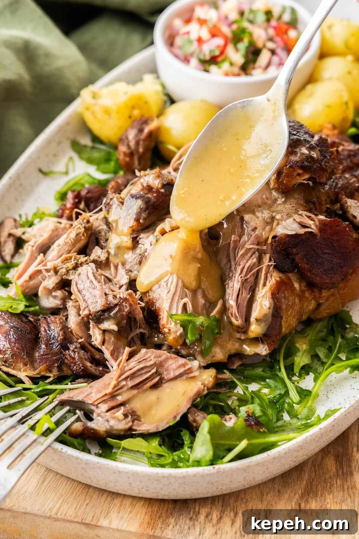 Top Easter Main Courses for a Memorable Holiday Meal 14 Platter with Slow Roasted Pork Shoulder being drizzled with gravy, with some rocket leaves and potatoes around the edge.