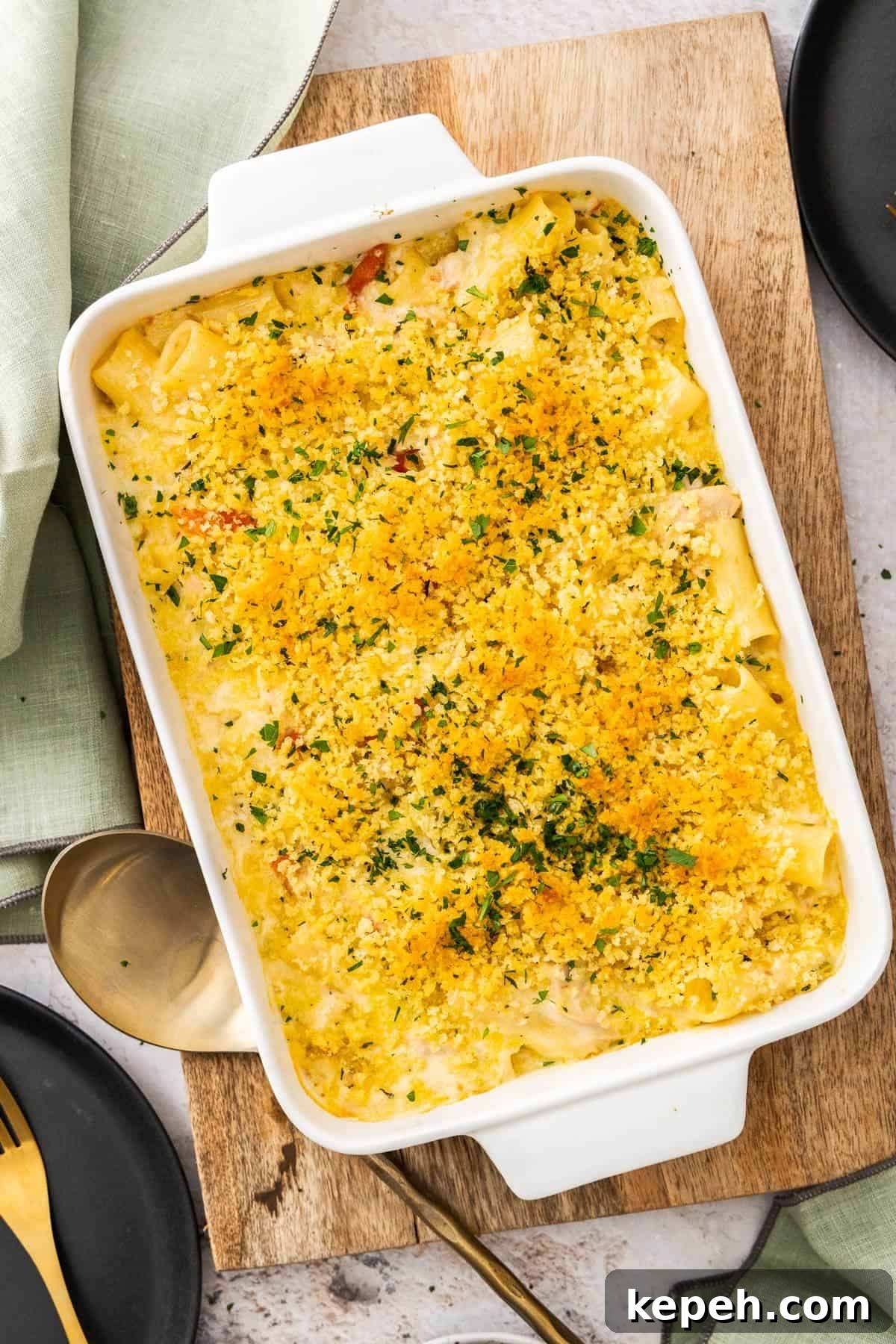 Top Easter Main Courses for a Memorable Holiday Meal 5 Large white rectangular dish of Creamy Tuna Pasta Bake, sitting on a wooden board, with a gold serving spoon on the edge.