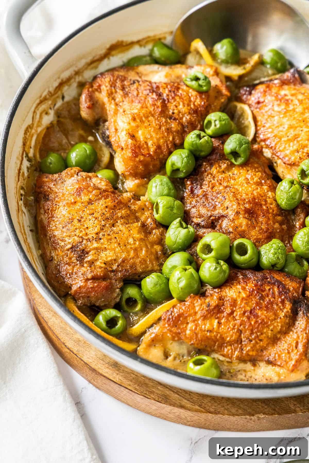 Top Easter Main Courses for a Memorable Holiday Meal 6 Round dish with the Braised Chicken,, Lemon and Olives, with a spoon resting in the dish.
