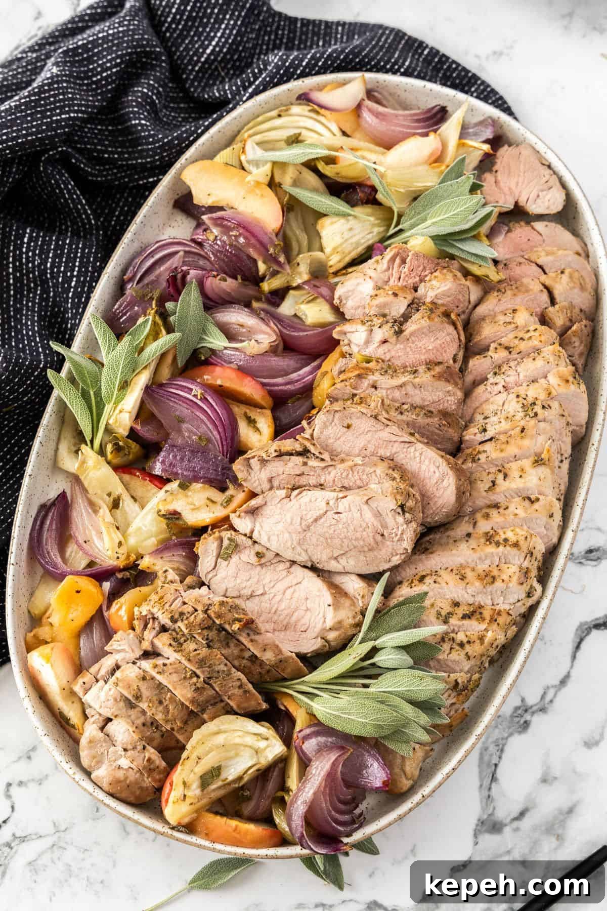 Top Easter Main Courses for a Memorable Holiday Meal 8 Platter of sliced Roasted Pork Tenderloin, surrounded by pieces of apple, fennel, onion and sage, with a black towel on edge.