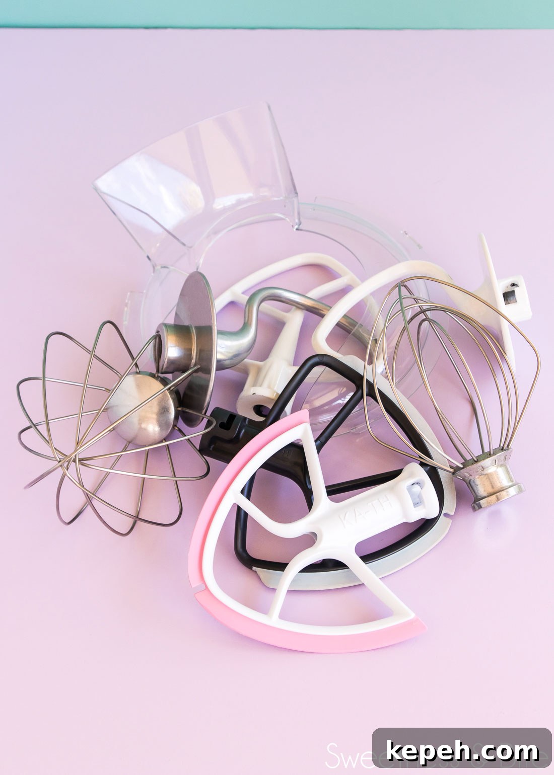 A jumble of stand mixer attachments on a purple background.
