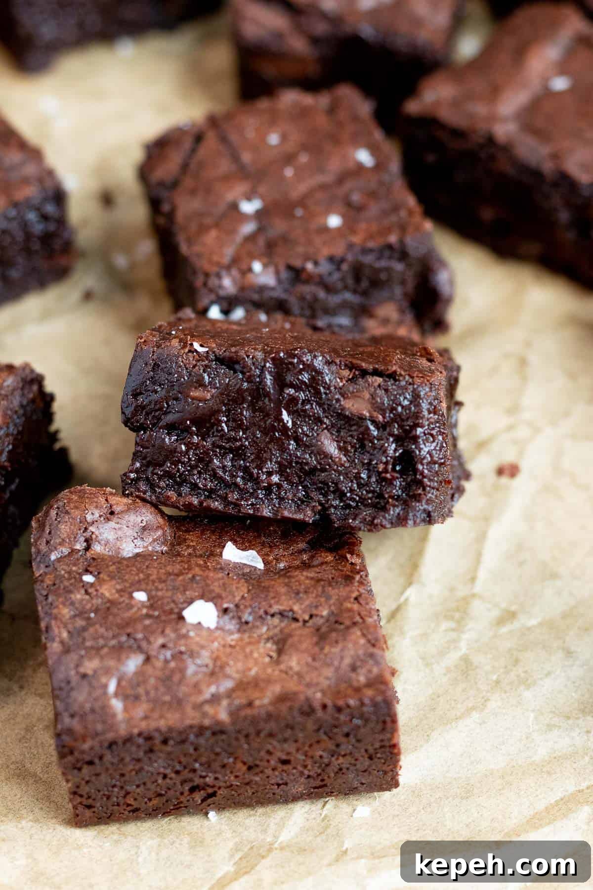 One-Bowl Dark Chocolate Brownies Recipe 4 dark chocolate brownie leaning on another brownie with sea salt on top