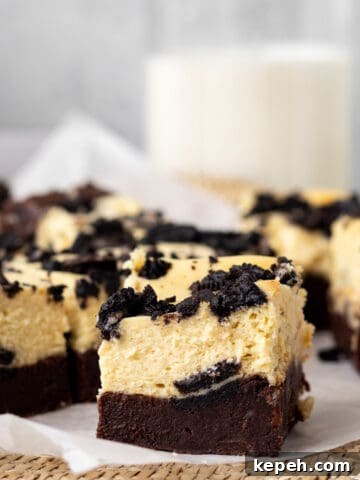 oreo cheesecake bars sliced into squares with a glass of milk in the background