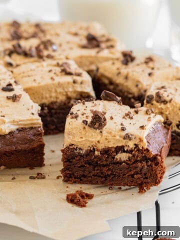 brownies with espresso frosting on top of a cooling rack with glasses of milk in background