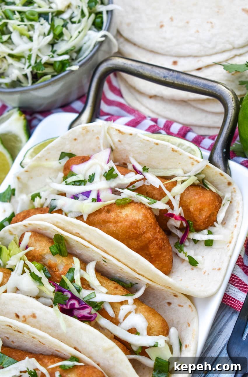 beer battered fish tacos arranged in a row on a white serving platter