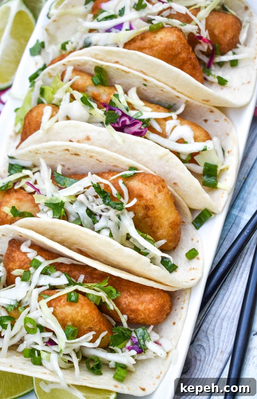 beer battered fish tacos arranged in a row on a white serving platter