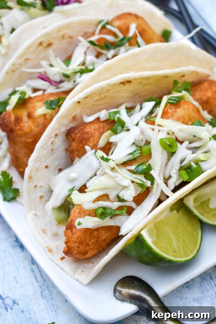beer battered fish tacos arranged in a row on a white serving platter