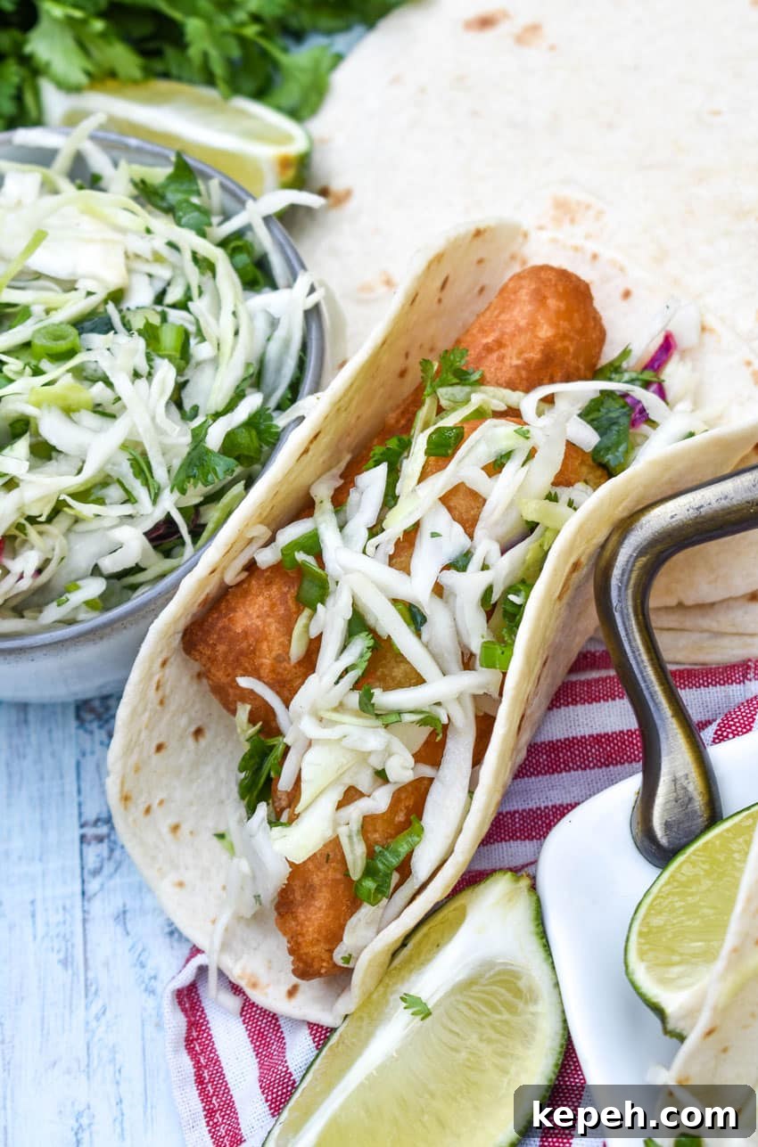 beer battered fish tacos arranged in a row on a white serving platter