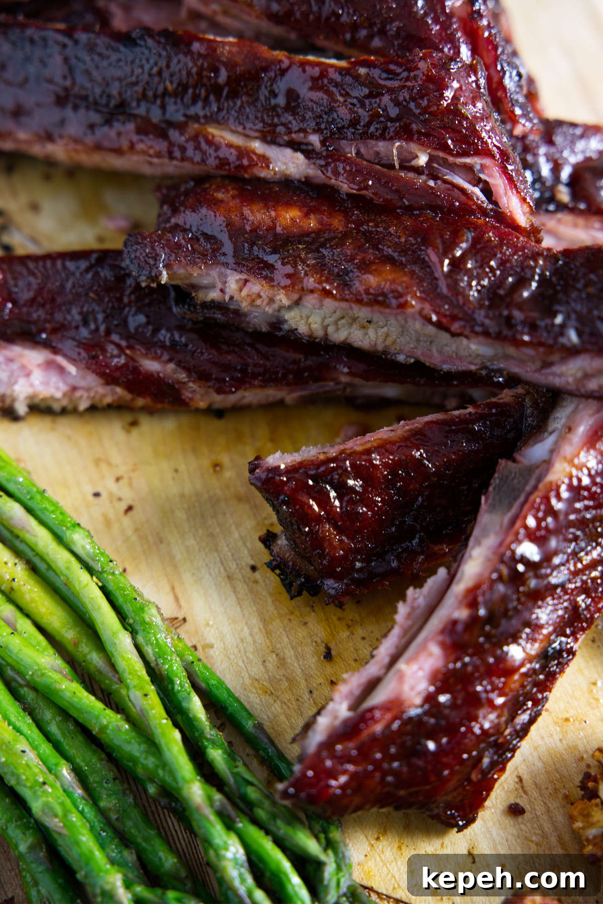 Perfect 3-2-1 Smoked Ribs Recipe for Tender, Fall-Off-the-Bone Results 9 sliced traeger 3-2-1 ribs on cutting board with asparagus