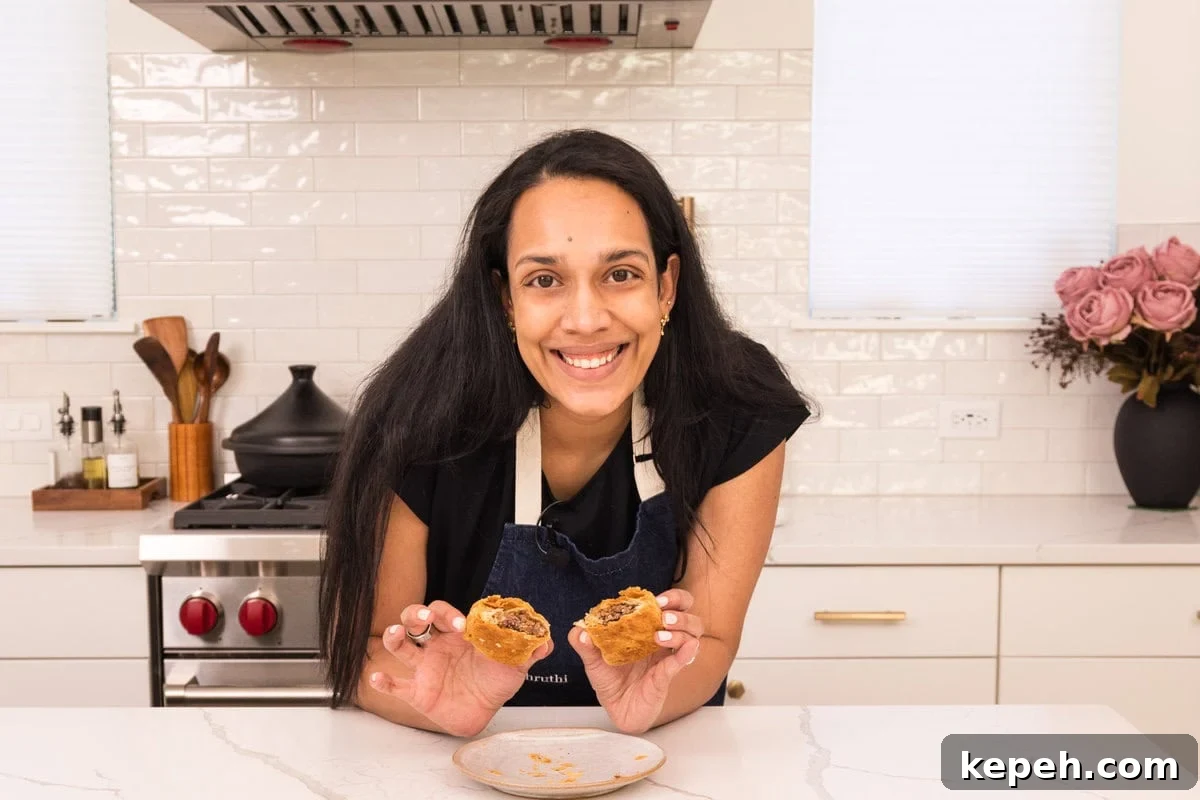 Authentic Jamaican Patty Recipe: Flaky Beef & Veggie Patties 5 Shruthi holding cooked Jamaican black bean patties