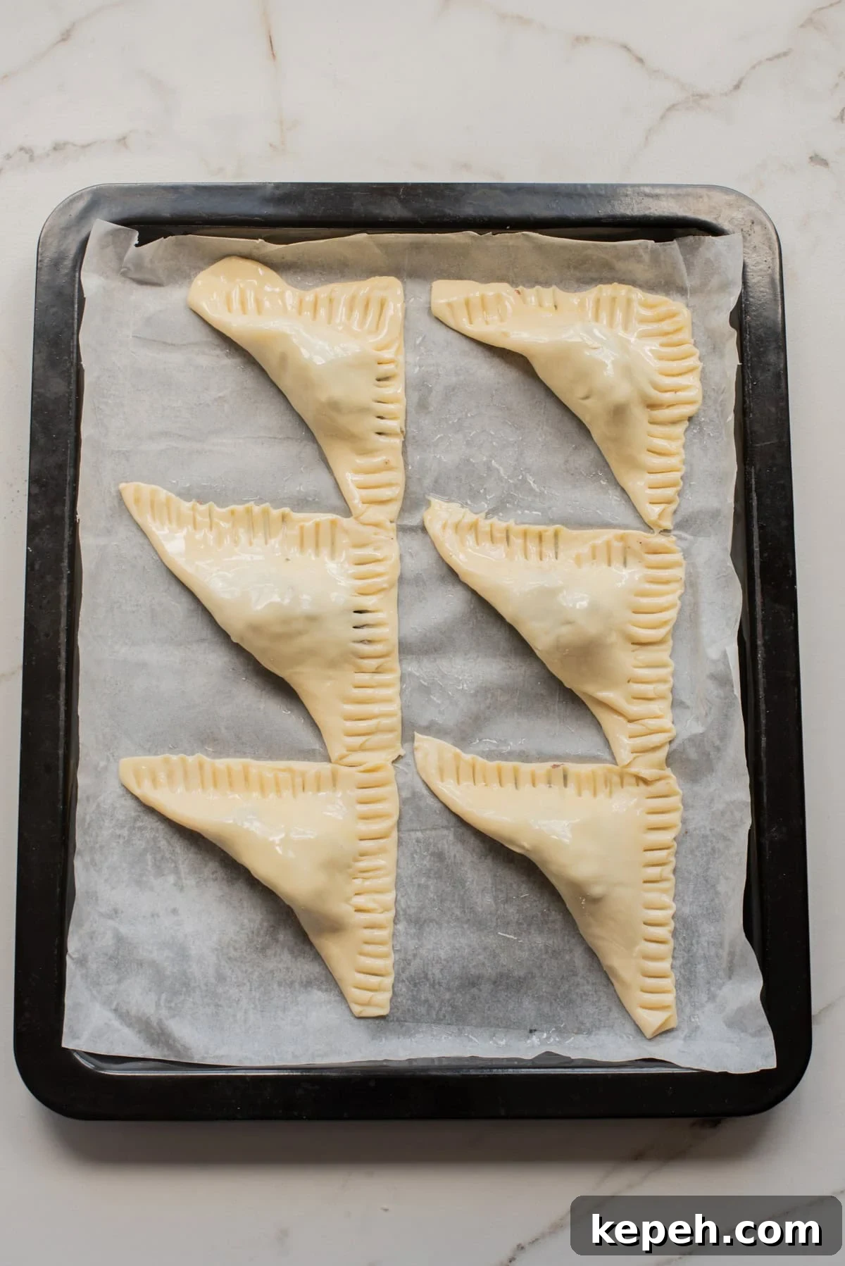 Authentic Jamaican Patty Recipe: Flaky Beef & Veggie Patties 8 Unbaked Jamaican jerk black-bean patties arranged on a parchment-lined baking tray.