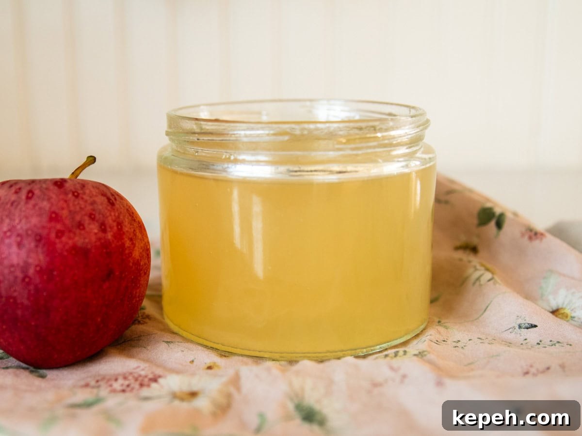 Homemade Apple Cider Vinegar Recipe for DIY Fermentation 2 A jar of homemade apple cider vinegar next to an apple.