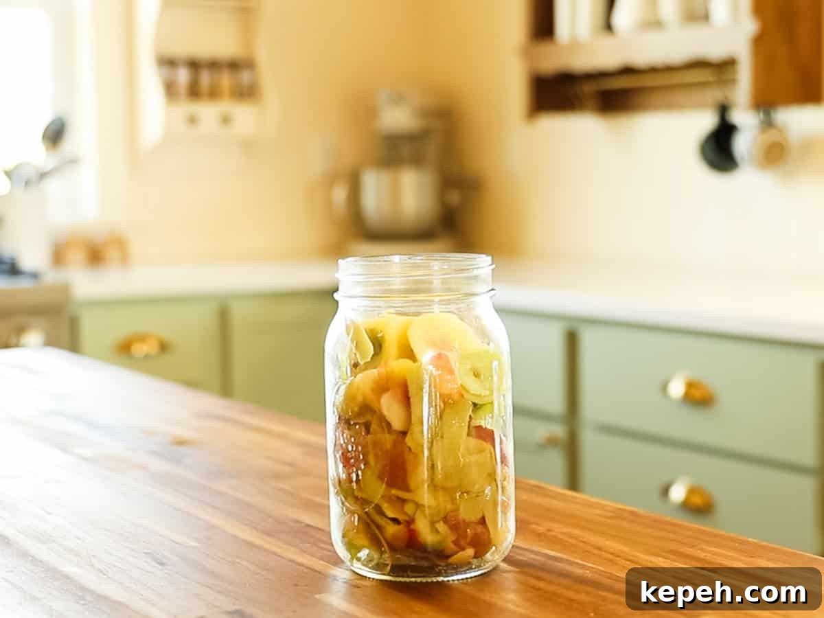 Homemade Apple Cider Vinegar Recipe for DIY Fermentation 4 Apple scraps in a mason jar on a kitchen table.