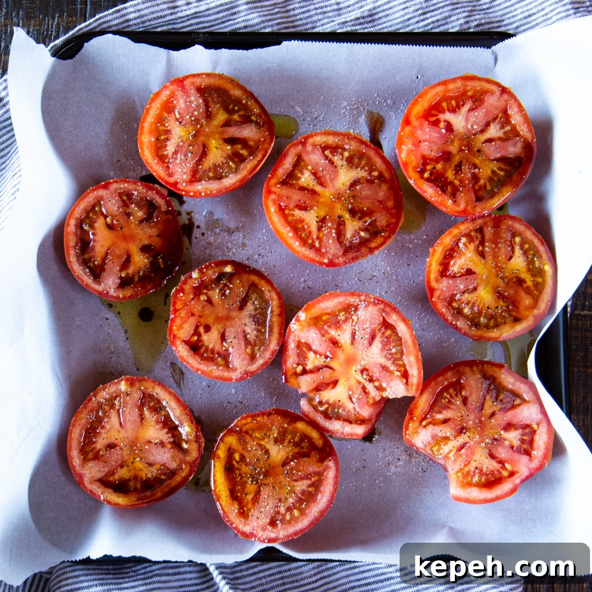 Balsamic-Roasted Tomatoes — Quick 5-Minute Prep Recipe 3 Tomato halves arranged on a baking sheet lined with parchment paper. They're dusted with salt and pepper and drizzled with olive oil and balsamic vinegar.