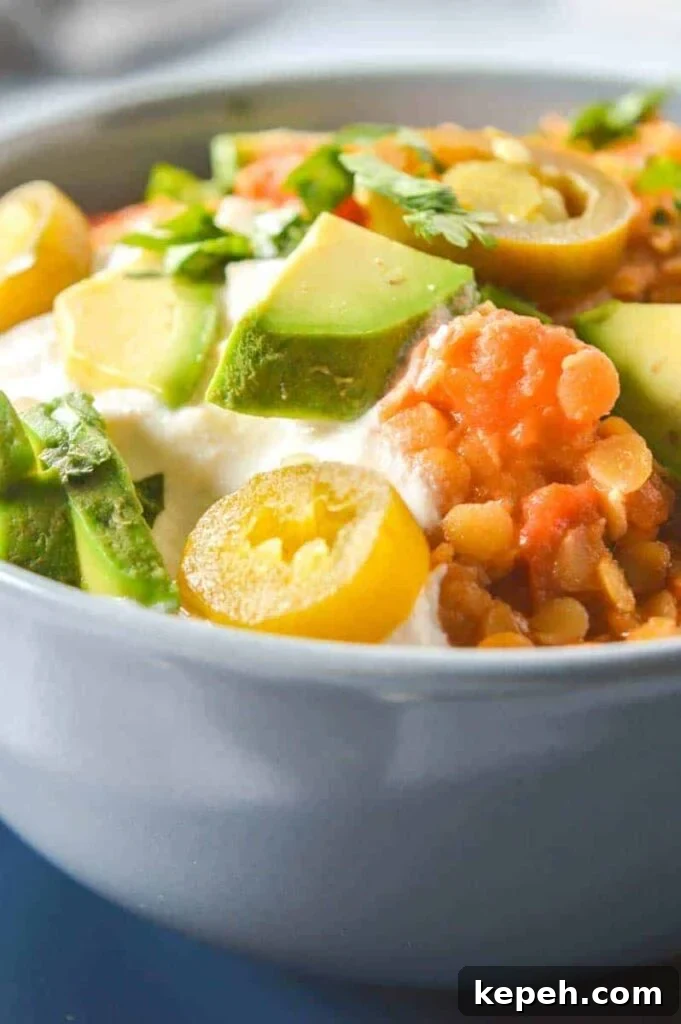 Hearty Red Lentil Chili with Smoky Tomatoes and Spices 2 Close up of red lentils and avocado in a grey bowl